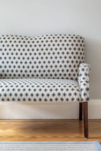 Small upholstered sofa in blue and grey print fabric with curved back